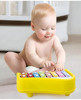 Baby sitting and happily playing the musical xylophone piano toy with bright color keys for early music learning